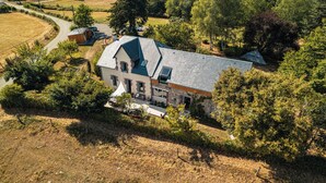 A large, two-story house with a sloped roof and a small attached garage. - Les jardins de Nanine (Lapleau)