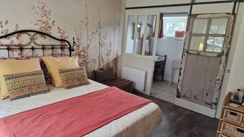 Een slaapkamer met een bed, een dressoir, een raam en een deur.