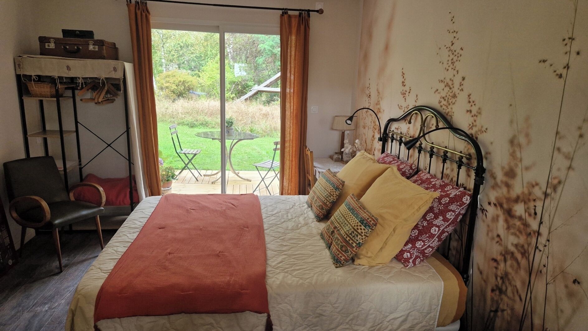 A bedroom with a bed, a chair, a table, and a view of the outdoors.