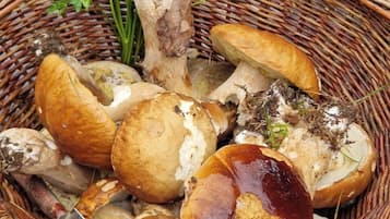 A wicker basket containing mushrooms and parsley on a wooden table.