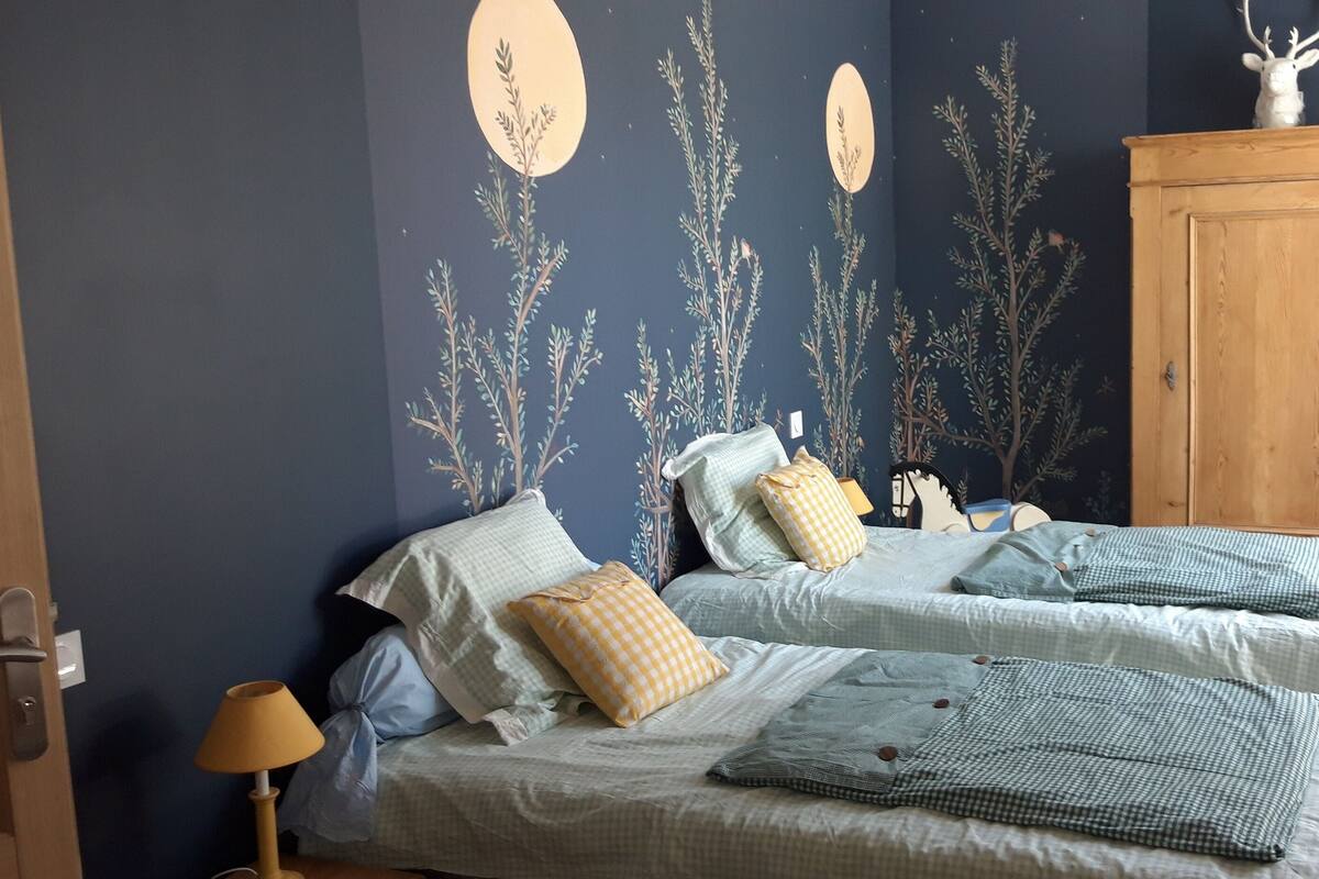 Un dormitorio con dos camas, un armario de madera y una silla.