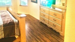 A bedroom with a bed, dresser, and a large mirror.