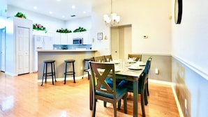 A modern kitchen with white cabinets, a central island, and bar stools.