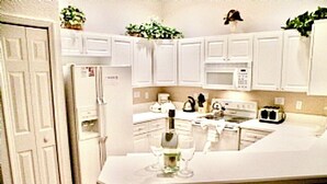 A kitchen with white cabinets, a refrigerator, a microwave, a stove, and a sink.
