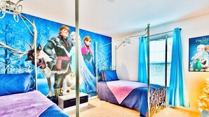 Ein Schlafzimmer mit einem Bett, einem Nachttisch und Wandgemälde mit Zeichentrickfiguren.