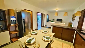 Une cuisine moderne avec un coin repas aménagé pour un repas, comprenant un réfrigérateur, un distributeur d’eau et une table à manger avec des assiettes et des verres déjà disposés.