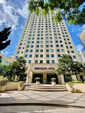 Un edifici d'hotel alt amb façana moderna, entrada destacada i un cel clar.