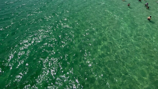 Une plage bordée d’une eau turquoise et transparente, avec, en arrière-plan, une série d’hôtels de grande hauteur.