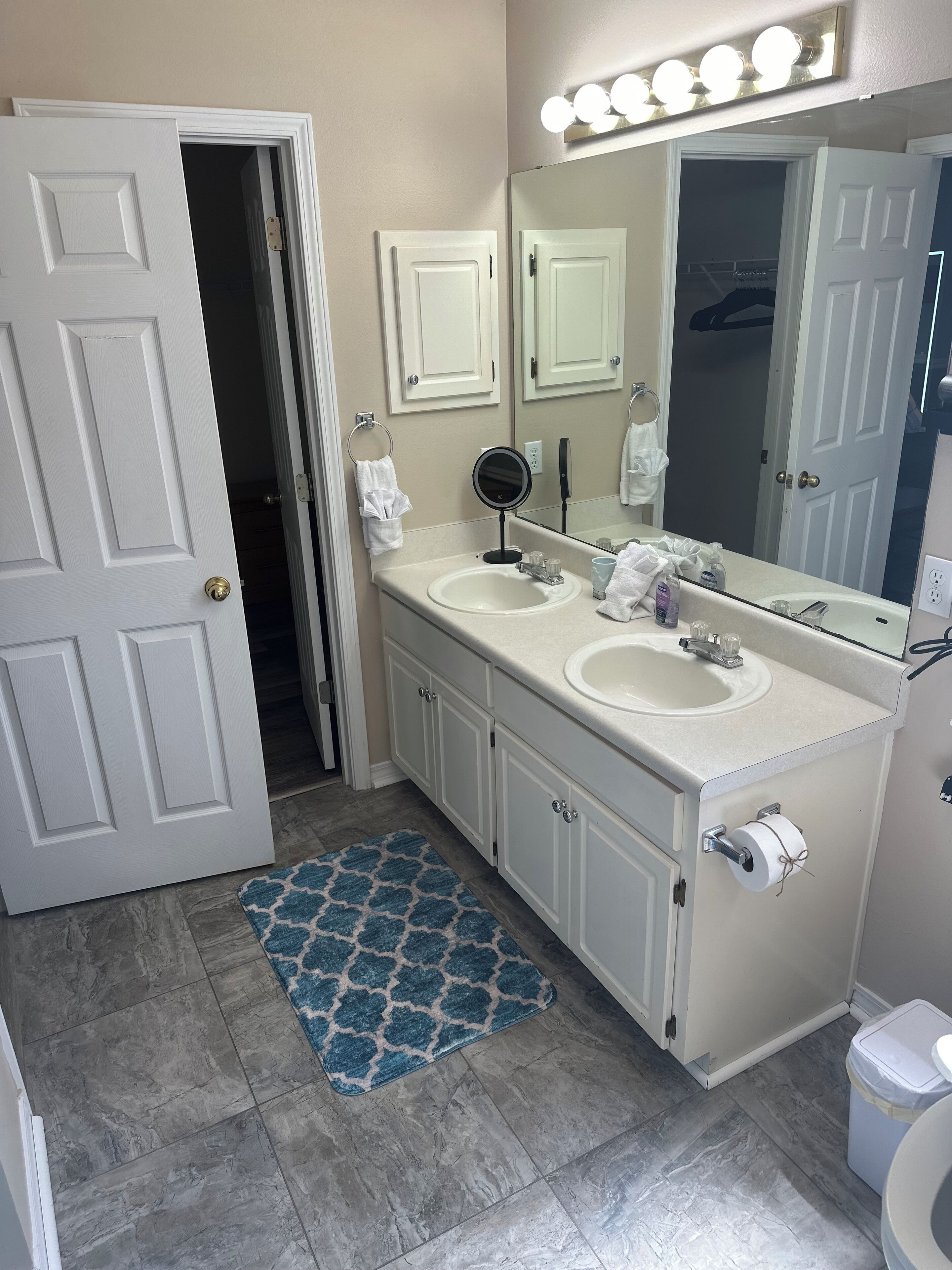 A bathroom with two sinks, a mirror, a towel rack, and a toilet.