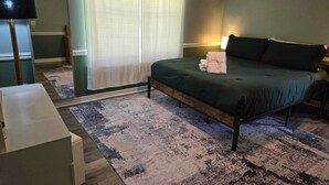 Une chambre à coucher avec un lit, une table de chevet, une lampe et une fenêtre avec des rideaux.