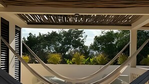 A hammock under a pergola with a view of trees and a patio area. - Jungle Escape: Cozy 1-Bedroom Retreat (Tulum)