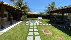 A backyard with a swimming pool, stone stepping paths, lounge chairs, and palm trees.