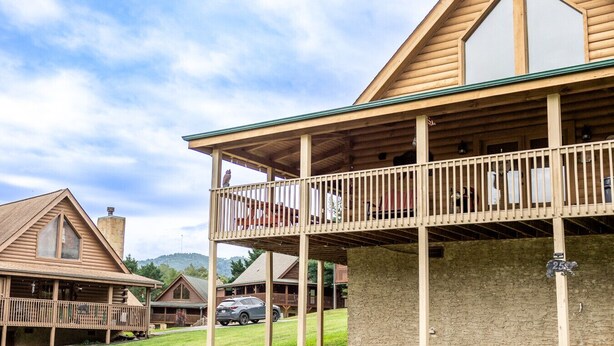 A wooden cabin with a balcony, a stone foundation, and a mountain backdrop. - Eagle Eye Cabin in the Smokies (Sevierville)