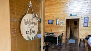 A wooden cabin interior with a welcome sign, wooden walls, a dining area, and a kitchen. - Eagle Eye Cabin in the Smokies (Sevierville)