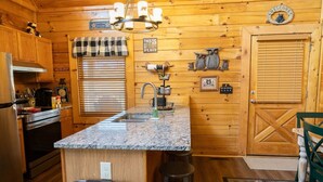 A wooden cabin-style kitchen with granite countertops, a built-in oven, and a sink. - Eagle Eye Cabin in the Smokies (Sevierville)