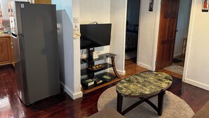Eine moderne Küche mit Kühlschrank, Flachbildfernseher und Holzkasten.