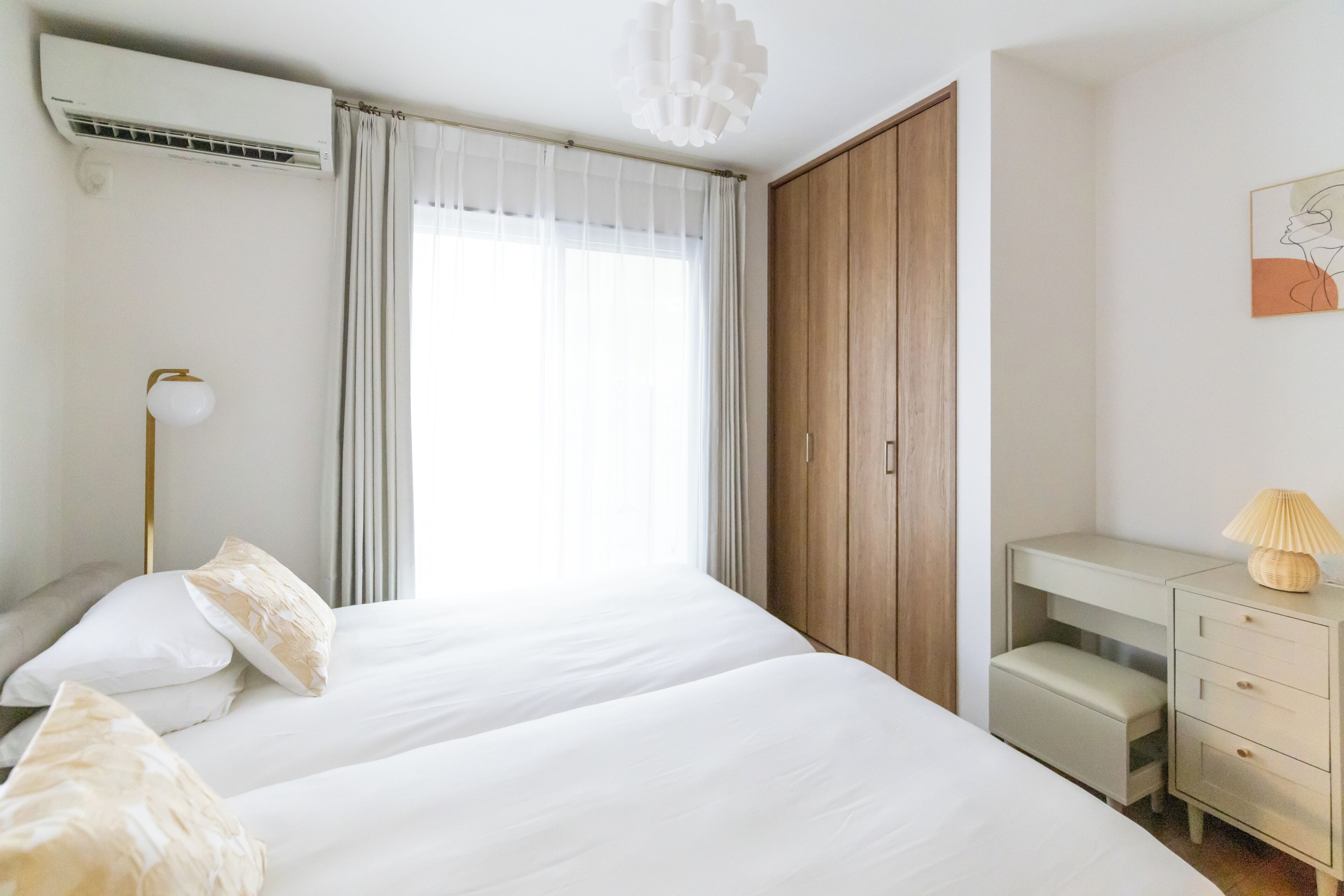 Een slaapkamer met een bed, nachtkastje, lamp en een garderobe.