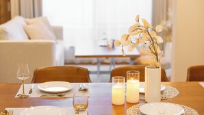 A dining table set with plates, cutlery, glasses, candles, and a vase with flowers. - It' ta de ChouChou - Self Check-In Only (Osaka)