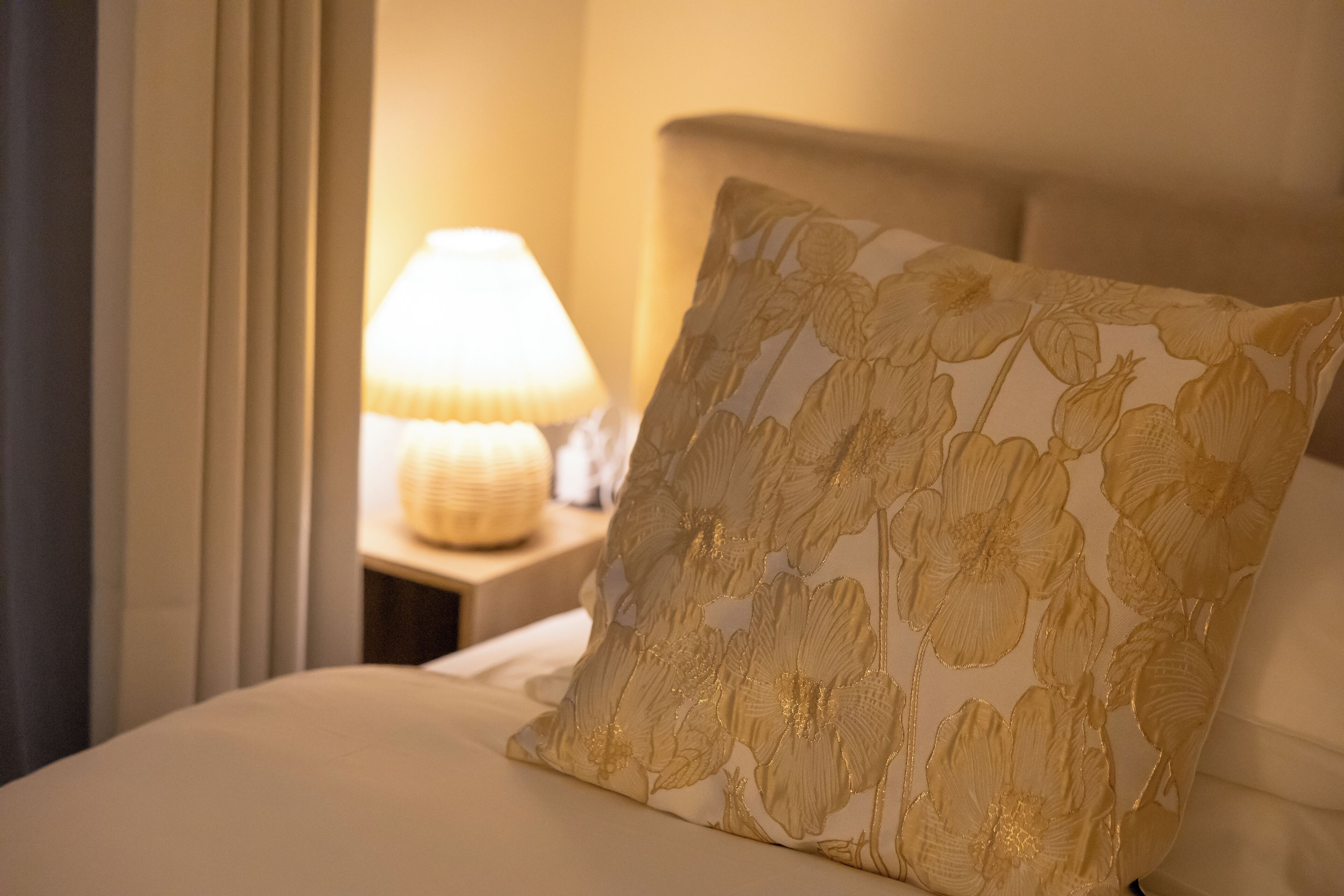 A bed with a floral pillow and a bedside lamp.