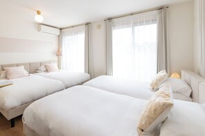 Une chambre d’hôtel avec deux lits, une table de chevet, une lampe et une fenêtre avec des rideaux.