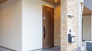 A modern entrance with a wooden door, a stone wall, and a mailbox. - It' ta de ChouChou - Self Check-In Only (Osaka)