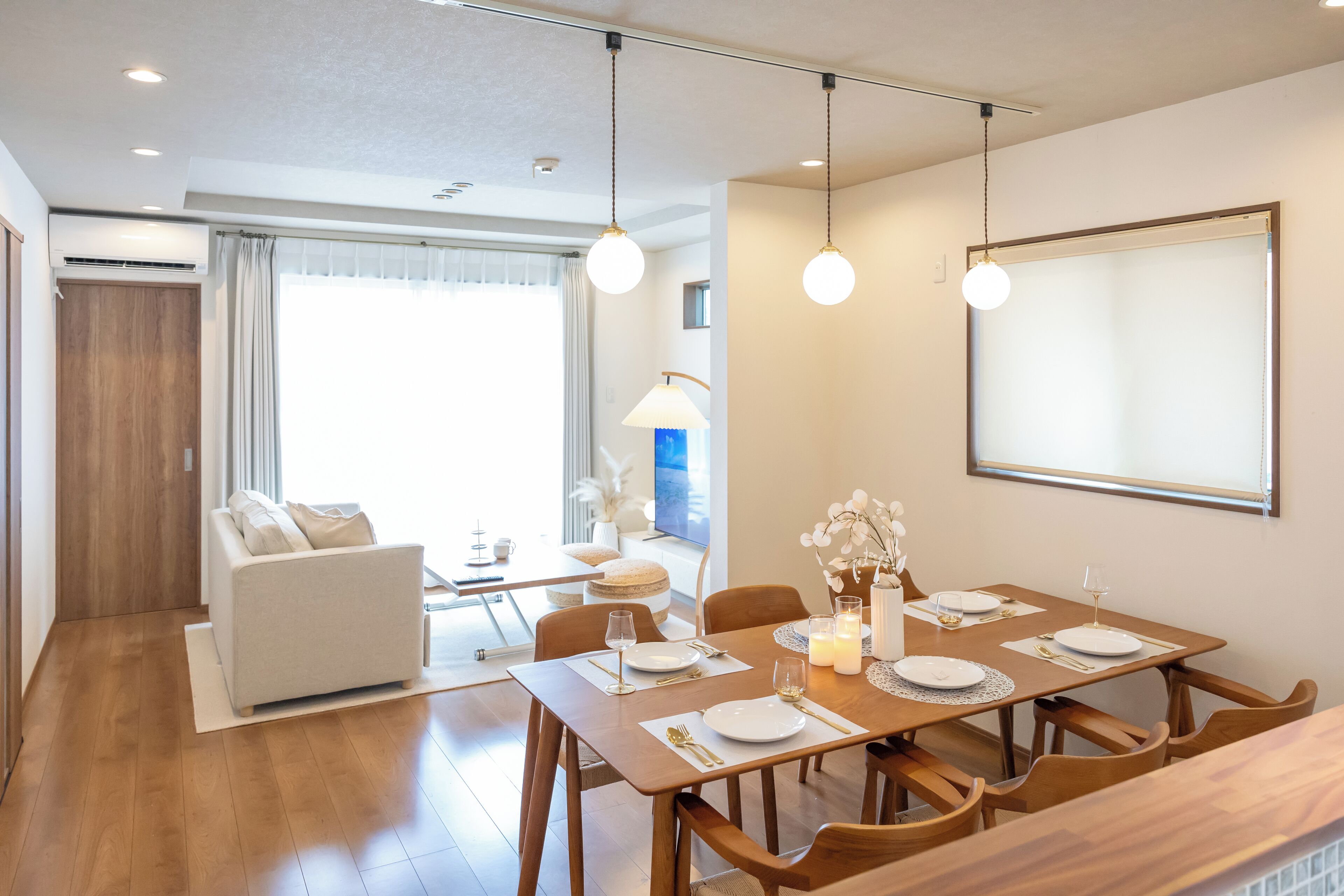 Un comedor moderno con una mesa de madera preparada para cuatro personas, rodeada de sillas de madera.