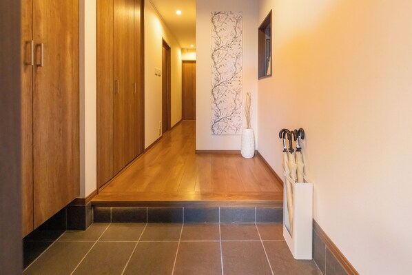 A hallway with wooden flooring, a tiled entrance, and a wall-mounted artwork.