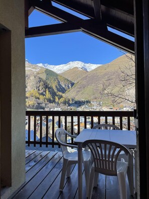 A wooden deck with a table and chairs overlooking a mountainous landscape with snow-capped peaks. - View village, balcony, parking, ski locker, 67m², Valloire (Valloire)