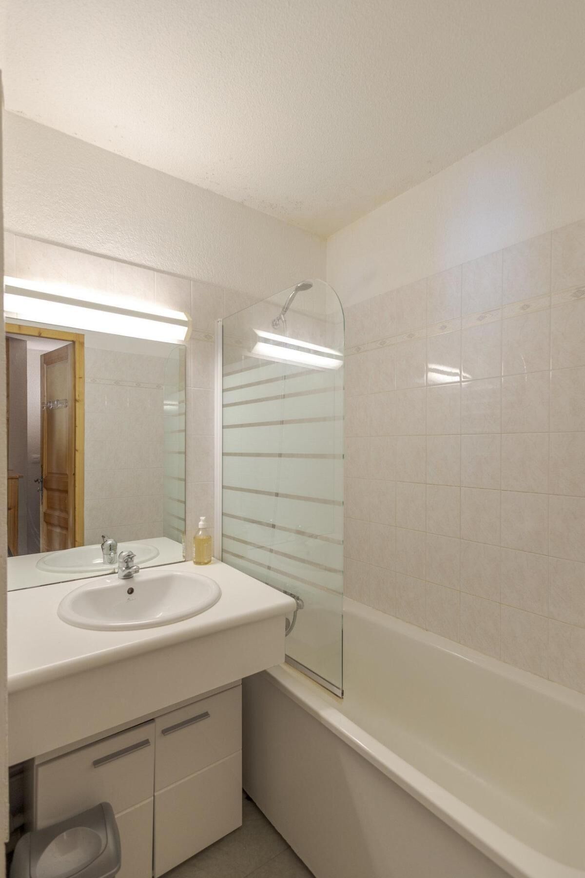 A bathroom with a white sink, mirror, and glass shower enclosure.