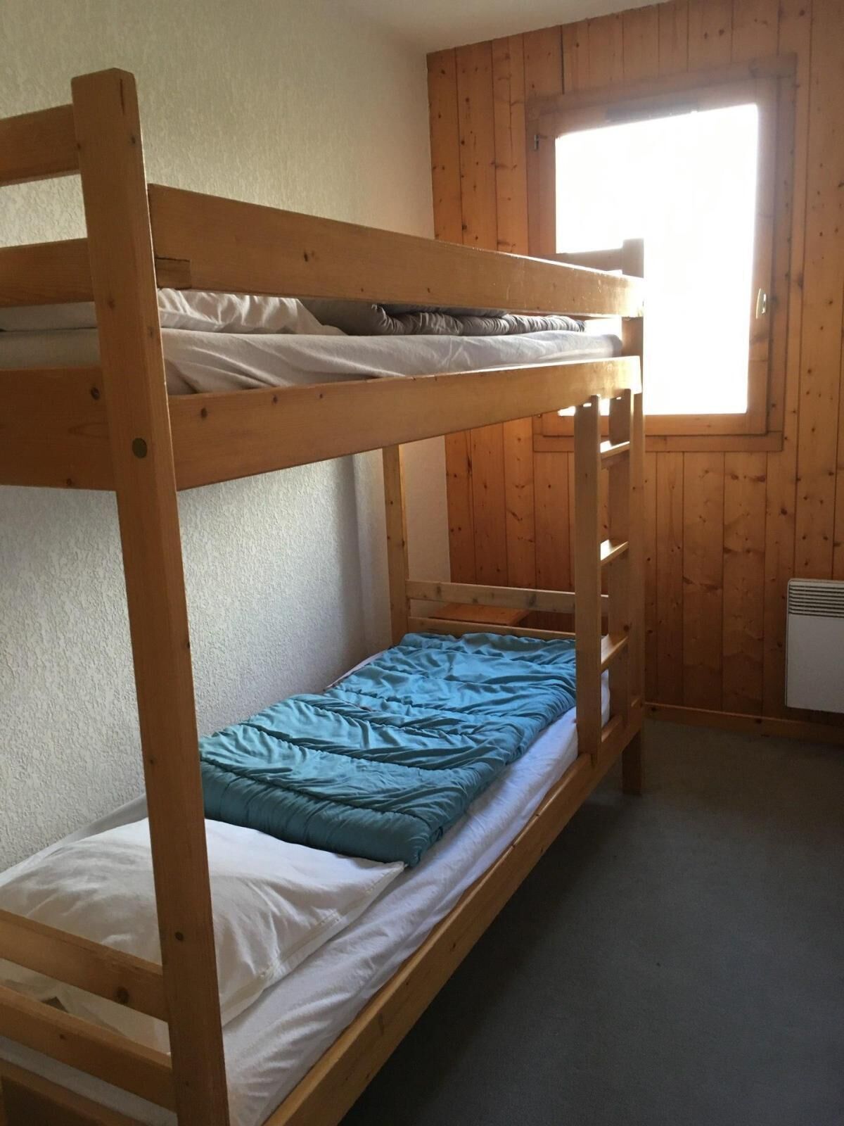 A bunk bed room with a window and a radiator.