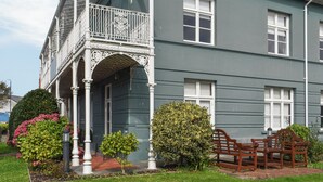 Ein zweistöckiges Gebäude mit Balkon und Garten.