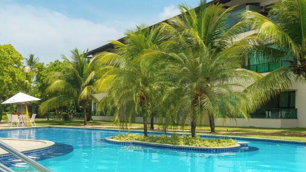 Ein Pool mit Palmen und Liegestühlen.
