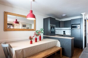 A modern kitchen with dark cabinetry, a wooden bench, and a table with a white tablecloth.