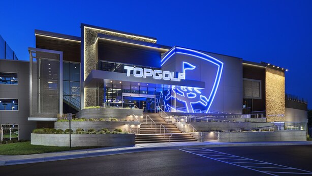 A modern building with a large illuminated sign reading "TOPGOLF".
