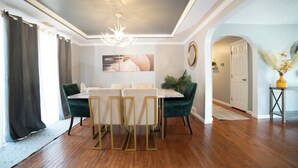A dining area with a table and chairs, a chandelier, and a potted plant.