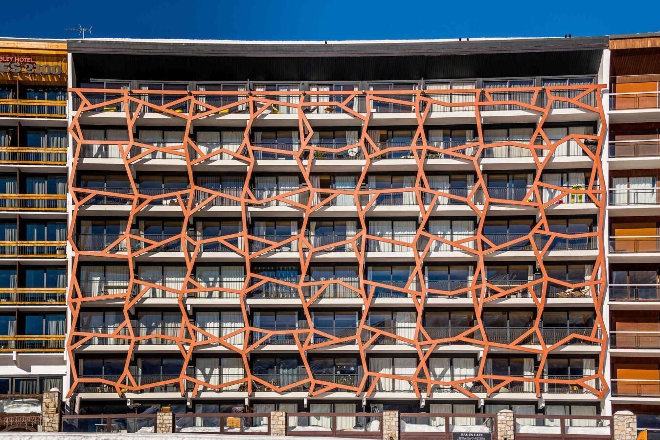 Un hôtel à plusieurs étages, doté d’une façade géométrique remarquable et de balcons.