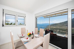 Un coin repas avec une table dressée pour deux personnes, une bouteille de vin et un saladier de fruits.