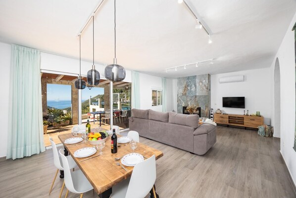 A modern living room with a sofa, dining table, and a TV.