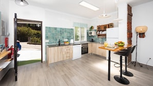 Una cocina moderna con comedor, armarios de madera, horno empotrado y un ventanal grande.