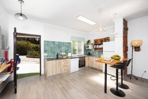 A modern kitchen with a dining area, wooden cabinets, a built-in oven, and a large window.