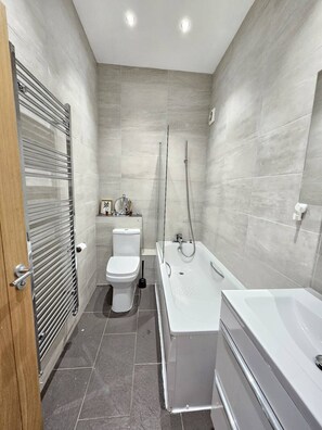 Een moderne badkamer met toilet, bad en douche.