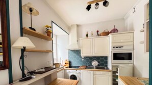 A compact kitchen with white cabinets, a wooden countertop, a washing machine, and a dining area with a wooden table and bench. - Spacious T2 in the heart of Chamonix (Chamonix-Mont-Blanc)