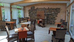 Un comedor acogedor con mobiliario de mimbre, paredes de piedra y ventanas amplias.