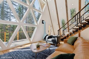 A spacious room with a large window, a staircase, a sofa, and a coffee table.