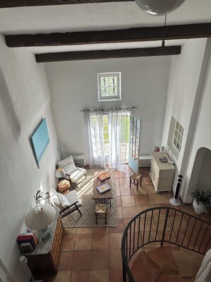 A spacious room with a high ceiling, a staircase, a dining area with a table and chairs, a sofa, a small cabinet, and a window. - Exklusive Landhausvilla, gr. Pool, gr. Garten, Ruhig, 5 Gehmin. zum Dorf (Bargemon)