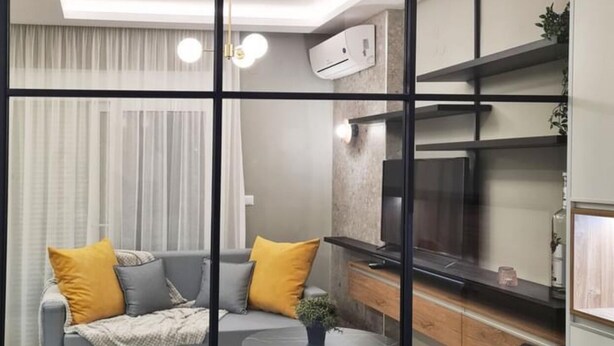A modern living space with a glass partition separating a dining area from a kitchen.
