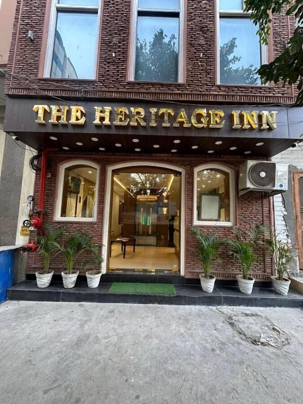 The exterior of The Heritage Inn, featuring a brick facade, large windows, and potted plants at the entrance.