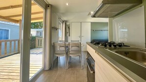 Eine moderne Küche mit Gasherd, Spüle und einem Essbereich mit Stühlen.