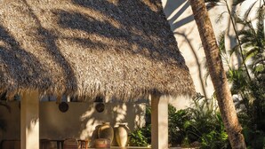 A poolside area with a thatched roof structure, lounge chairs, and a water feature. - Esh Hotel and Spa, a Member of Design Hotels (Nosara)