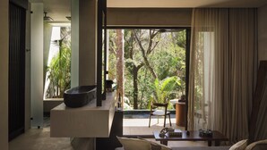 Un intérieur moderne avec une grande fenêtre, un bol noir posé sur une étagère, une chaise en bois et une table avec une bouteille et des verres.